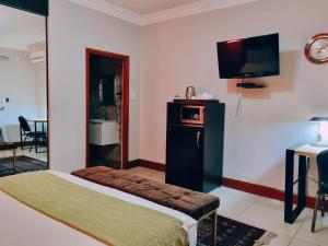 a hotel room with a bed and a flat screen tv at Red Apple Guest House in Pretoria