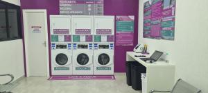 a laundry room with a purple wall with washing machines at Flat Pasárgada 712, Free Bikes, pé na praia in Vila Velha