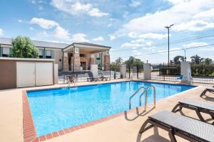 een zwembad met tafels en stoelen naast een gebouw bij Best Western Bayou Inn in Westwego