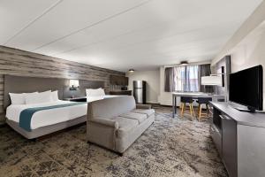 a hotel room with a bed and a couch and a television at Best Western Parkway Hotel Toronto North in Richmond Hill