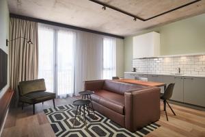 ein Wohnzimmer mit einem braunen Sofa und einer Küche in der Unterkunft Corendon Apartments Amsterdam Schiphol Airport in Badhoevedorp