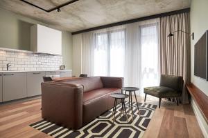 a living room with a brown couch and a kitchen at Corendon Apartments Amsterdam Schiphol Airport in Badhoevedorp