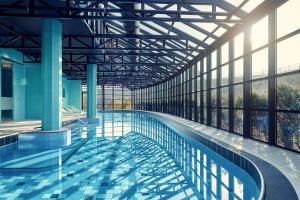a swimming pool in a building with large windows at Corendon Apartments Amsterdam Schiphol Airport in Badhoevedorp