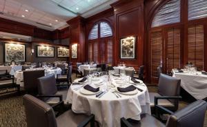 a dining room with white tables and chairs at Hilton Naples in Naples
