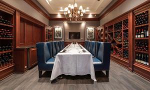 a dining room with a table and blue chairs and wine bottles at Hilton Naples in Naples
