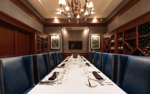 a dining room with a long table and blue chairs at Hilton Naples in Naples