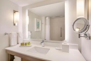 a white bathroom with a sink and a mirror at Hilton Naples in Naples