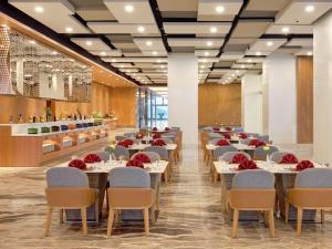 a restaurant with tables and chairs in a room at Grand Mercure Lampung in Bandar Lampung