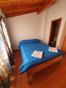 Una cama en una habitación con una manta azul encima. en Alojamientos ANSAI 1, en El Bolsón 2 fotos más