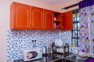 a kitchen with wooden cabinets and a microwave at A&B Cozy Retreat Kitale in Kitale
