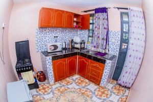 a small kitchen with orange cabinets and a tile floor at A&B Cozy Retreat Kitale in Kitale