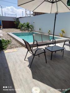 2 sillas y sombrilla junto a la piscina en Tumbes Zorritos Bocapan Casa con piscina 3 dormitorios, en Bocapán