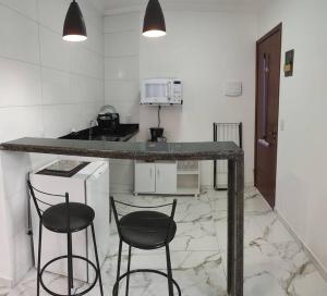 a kitchen with two stools and a counter in a room at Casa Nova no Centro de Penedo-Quitinete in Penedo +6 photos