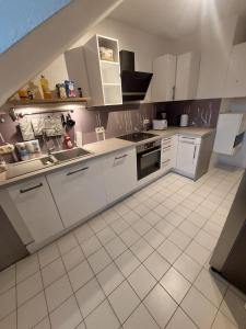 a kitchen with white cabinets and white tile floors at Reinfeld Zentral in Reinfeld