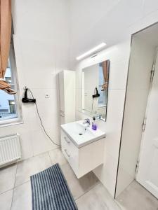 een witte badkamer met een wastafel en een spiegel bij Spacious 2BDR apartment with balcony in Wenceslas Square in Praag
