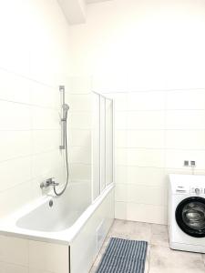 een badkamer met een bad en een wasmachine bij Spacious 2BDR apartment with balcony in Wenceslas Square in Praag