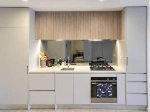 cocina con armarios blancos y fogones en Modern Elegance: 2 Bedroom Oasis w/ Free Parking, en Epping