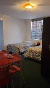 Cette chambre comprend deux lits, un bureau et une table. dans l'établissement DON ALEJANDRO, à Trujillo