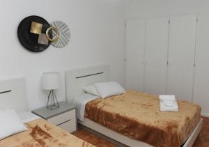 a white bedroom with two beds and a fan at APARTAMENTO CENTRAL in Mondim de Basto