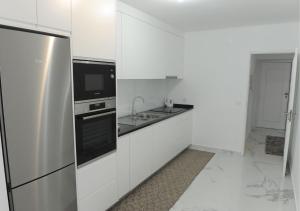 a white kitchen with a sink and a refrigerator at APARTAMENTO CENTRAL in Mondim de Basto