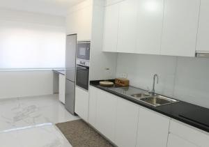 a white kitchen with a sink and a counter at APARTAMENTO CENTRAL in Mondim de Basto