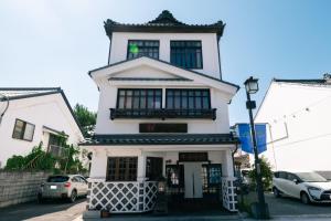 a white building with a balcony on top of it at Nunoya Ryokan in Matsumoto
