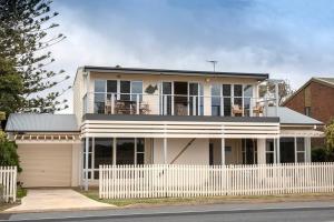 una casa blanca con una valla blanca delante de ella en PORT WILLUNGA DREAMING a beach front experience, en Port Willunga