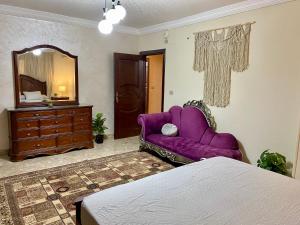 Cozy 3BR Apartment in Maadi في القاهرة: غرفة نوم مع أريكة أرجوانية ومرآة