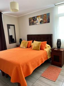 a bedroom with a bed with an orange blanket at Depto Ginebra 1 dorm con estacionamiento in Temuco