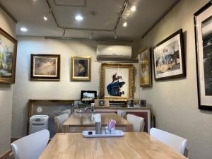 un restaurante con mesa, sillas y cuadros en la pared en Gallery Compass, en Osaka