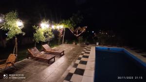 a patio with two chairs and a pool at night at aires de montaña in Ciudad Lujan de Cuyo