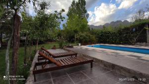 a wooden bench sitting next to a swimming pool at aires de montaña in Ciudad Lujan de Cuyo