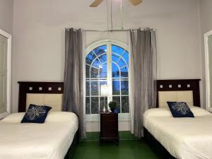 two beds in a room with a window at Hostal CasaBlanca in Ciudad Valles