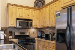 a kitchen with wooden cabinets and a stainless steel refrigerator at Antler Way at Lakota,,,, townhouse in Winter Park
