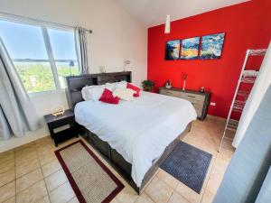 een slaapkamer met een groot bed met een rode muur bij Paradise Beach Home @Jobos beach in Isabela