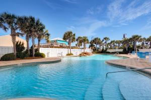a swimming pool with palm trees in a resort at Majestic Resort! Newly Updated Beachfront 3BR Condo in Panama City Beach