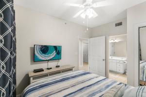 a bedroom with a bed and a tv on the wall at Majestic Resort! Newly Updated Beachfront 3BR Condo in Panama City Beach