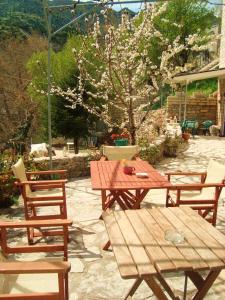 a wooden picnic table and chairs and a tree with flowers at Casa Lanoi in Syrrako