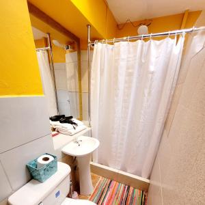 a bathroom with a white shower curtain and a toilet at wayra house san blas in Cusco