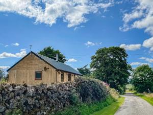 a barn with a stone wall next to a road at The Barn in Lairg