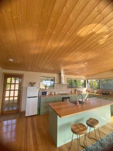 a kitchen with a wooden ceiling and a counter with stools at Evergreen Cabin in Primrose Sands