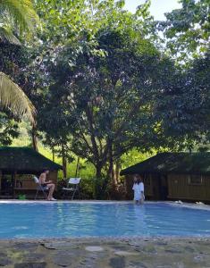 un par de personas de pie en una piscina en Rea's Bamboo Resort, 