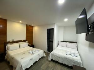 a hotel room with two beds and a flat screen tv at Hotel Yolima Real in Bogotá