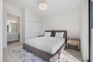 a white bedroom with a bed and a night stand at Beachfront Luxury Suite #21 at THE BEACH HOUSE in Campbell River