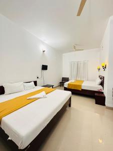 Duas camas num quarto branco com amarelo e branco em Pknhomestay kumily thekkady em Thekkady