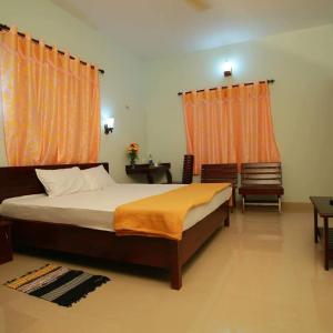 a bedroom with a large bed with orange curtains at Pknhomestay kumily thekkady in Thekkady