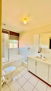 a bathroom with a toilet and a tub and a sink at Early Australian Motor Inn in Mildura