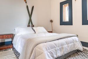 a bedroom with a white bed with a blanket on it at Lodge Pochoco Refugio de Montaña in Santiago
