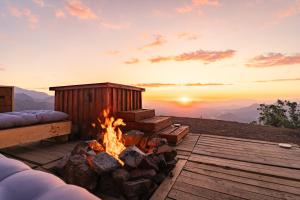 a fire pit on a deck with the sunset in the background at Lodge Pochoco Refugio de Montaña in Santiago