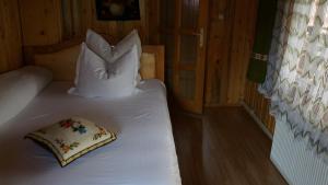 a bedroom with a white bed with a pillow on it at Pensiunea Maria in Rohia +4 photos